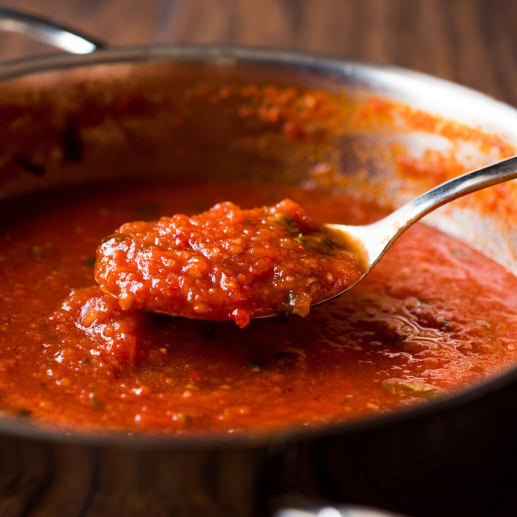 A spoon dipped into a pot of homemade pasta sauce.