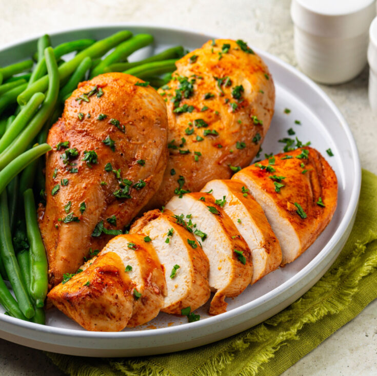 baked chicken breast on plate sliced with green beans