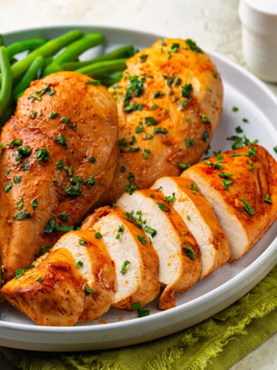 Baked chicken breast with green beans on the side.
